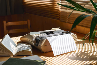 Retro typewriter on wooden table in tropical cozy setting near the window. 