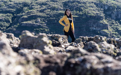 Full length of young woman standing on rock