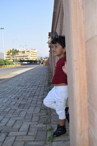 Side view of smiling young woman standing against building