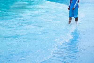 Low section of people standing in sea