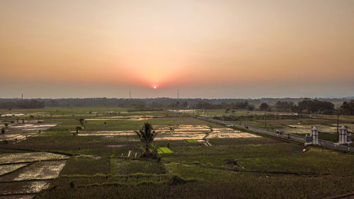 Scenic view of agricultural field against sky during sunset