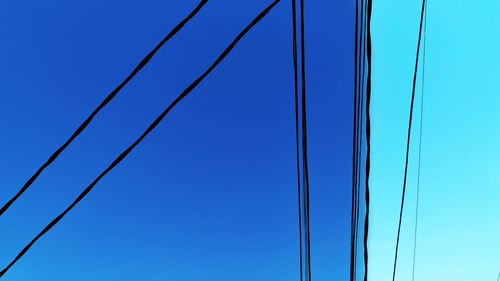 Low angle view of power lines against clear blue sky