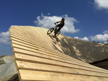 Low angle view of man riding mountainbike against sky