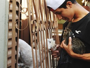 Side view of teenage boy with kitten and puppy