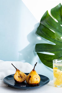 Healthy food concept. modern still life, monstera palm leaf, pears baked in caramel syrup, lemonade