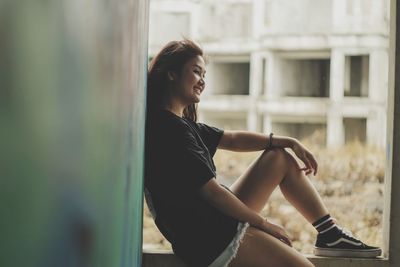 Side view of young woman looking through window