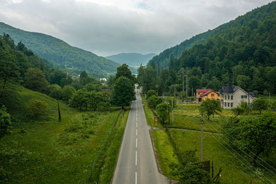 Road going through the village, mountains and forest in the summer time.