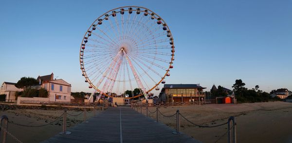 Boardwalk and ferris wheel at beach against sky