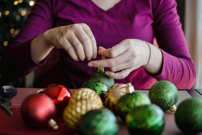 Midsection of woman preparing baubles on table