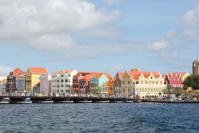 Buildings by river against sky in city