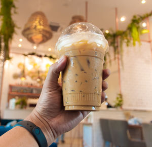 Close-up of hand holding drink served on table