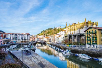 River by buildings in city against sky