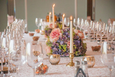 Close-up of flowers and candles on dining table