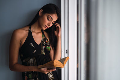 Young woman looking away while standing on wall