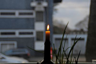 Close-up of illuminated candle against building