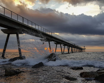 Bridge over sea against sky during sunset