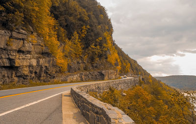 Road amidst trees against sky during autumn