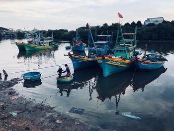 Boats moored at harbor against sky