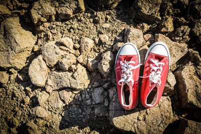 Directly above of red canvas shoes on rocks