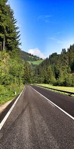 Empty road by trees against sky