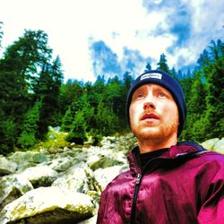 Portrait of young man standing against trees in forest