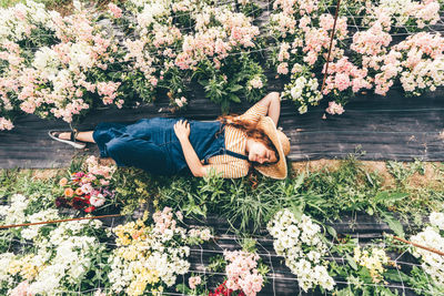 Woman lying near colorful flowers in modern greenhouse on nice day .