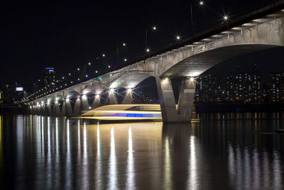 Boat moving below illuminated wonhyo bridge over han river at night