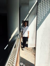 Portrait of man standing on railing against wall