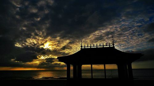 Silhouette built structure against sky at sunset