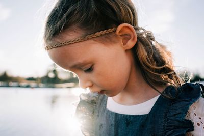 Close up of a girl with a feather headband on at sunset by the water