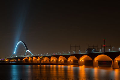 Low angle view of illuminated bridge over river at night