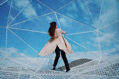 Full length of woman standing against blue sky