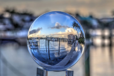 Close-up of crystal ball on river against cityscape