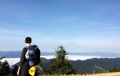 Rear view of woman standing on mountain against sky