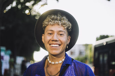 Portrait of happy young man with curly hair wearing hat