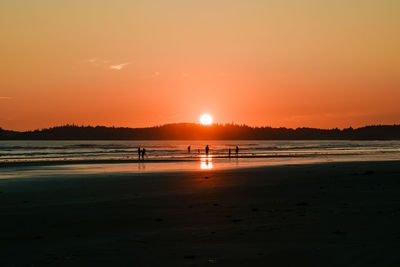 People standing at a magical sunset at long beach on vancouver island.