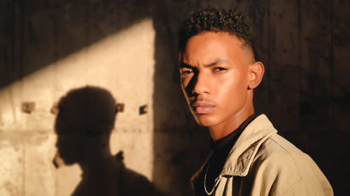 Portrait of young man standing against wall