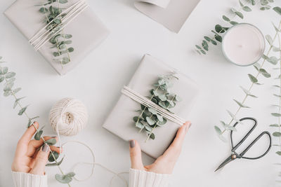 Cropped hands of woman holding gift box over white background