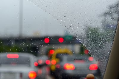 Cars on road seen through wet window in rainy season