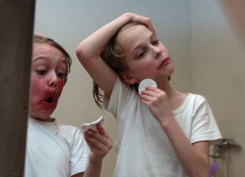Portrait of kids, cleaning their face at home against miror