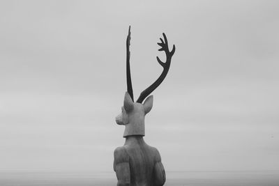 Statue by sea against sky