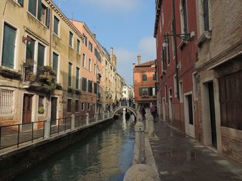 Canal in city against sky