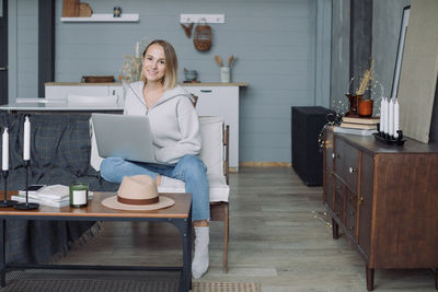 Full length of woman using phone while sitting on table