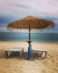 Deck chairs on beach against sky