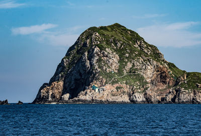 Rock formations by sea against blue sky