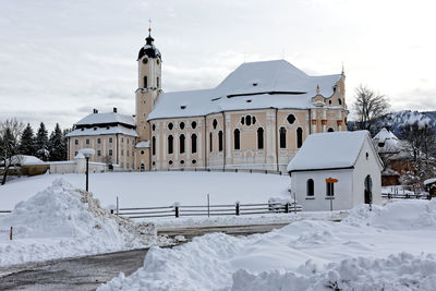 Empty road amidst snow covered field leading towards wies church at winter