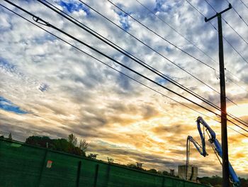 Low angle view of electricity pylon against dramatic sky