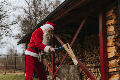 Man wearing santa costume chopping wood