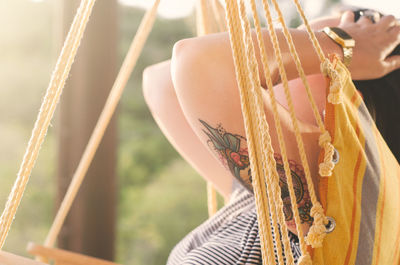 Side view of woman with hand in hair while relaxing on hammock