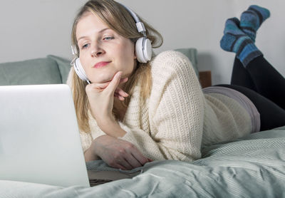 Midsection of man using mobile phone while sitting on bed at home